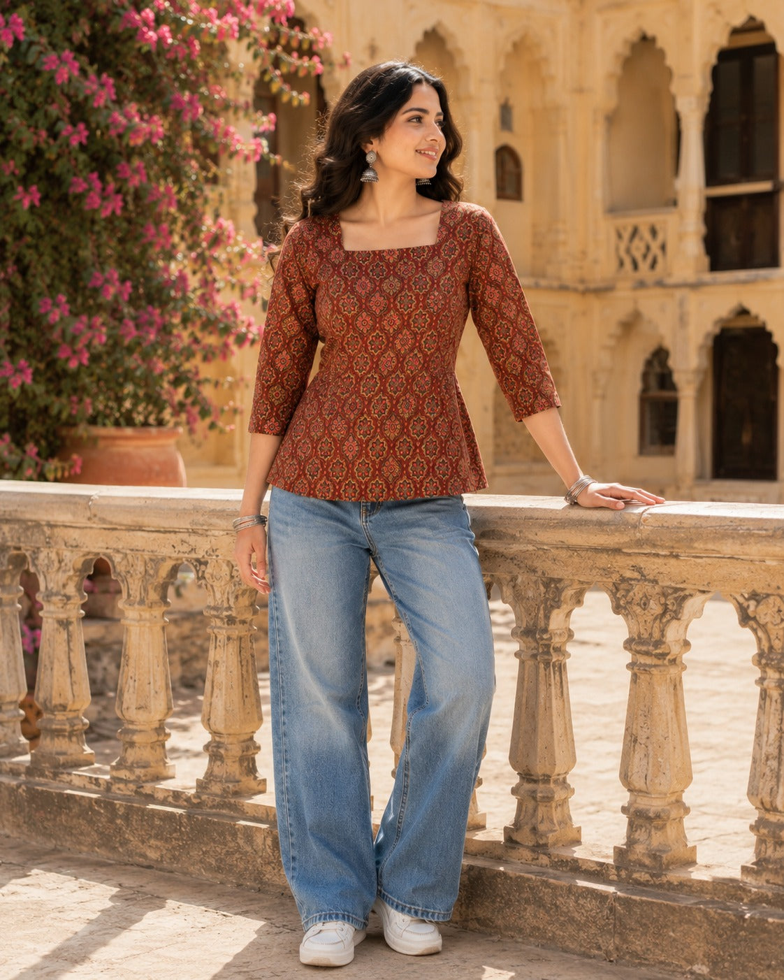 Woman standing wearing maroon Ajrakh printed square neck top with fitted waist, styled with wide-leg jeans