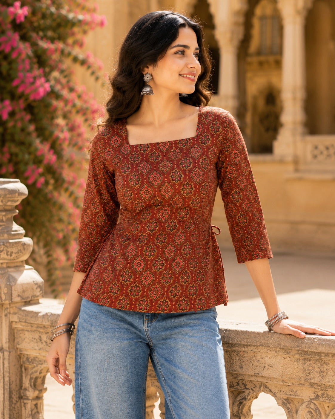 Woman wearing maroon Ajrakh printed square neck top with 3/4 sleeves and tie-back detail, paired with blue jeans - front view